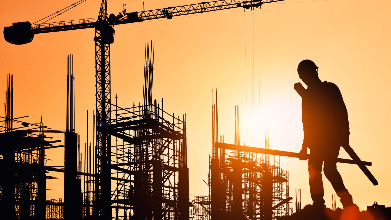 Obrero en una estructura en construcción al atardecer