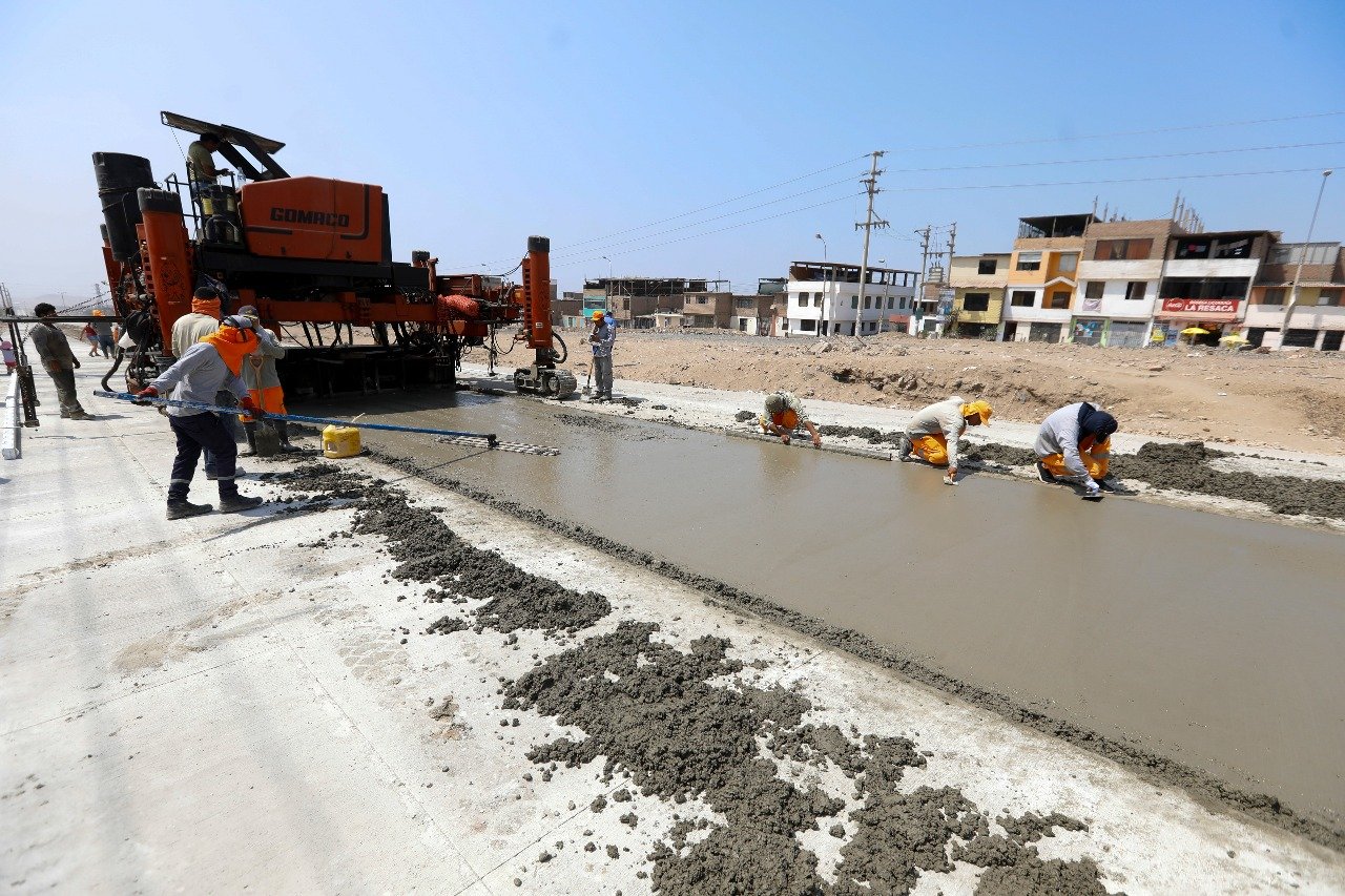 Cuadrilla vaciando concreto en una losa de pavimento con maquinaria