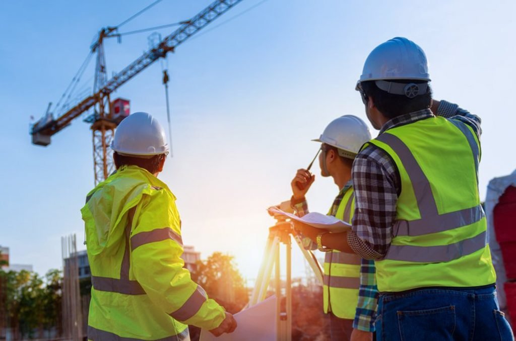 Ingenieros con casco supervisando una obra con grúas