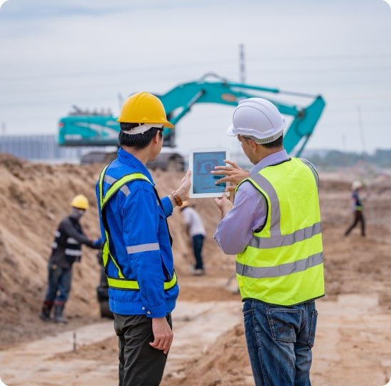 Supervisores con tablet en obra y una excavadora al fondo