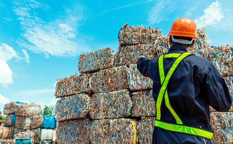 Trabajador junto a fardos de material reciclable